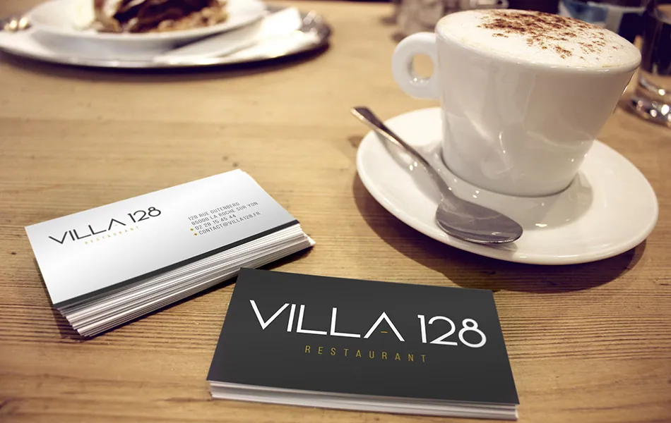 Cartes de visite Villa 128 noires et blanches posées à côté d'un café